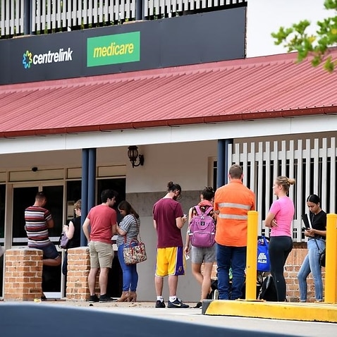 People are seen in a long queue outside a Centrelink office