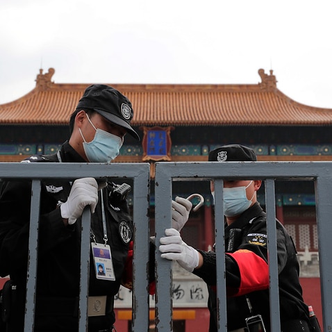 Security guards wearing protective face masks to prevent the spread of the new coronavirus lock the gate of the Forbidden City in Beijing