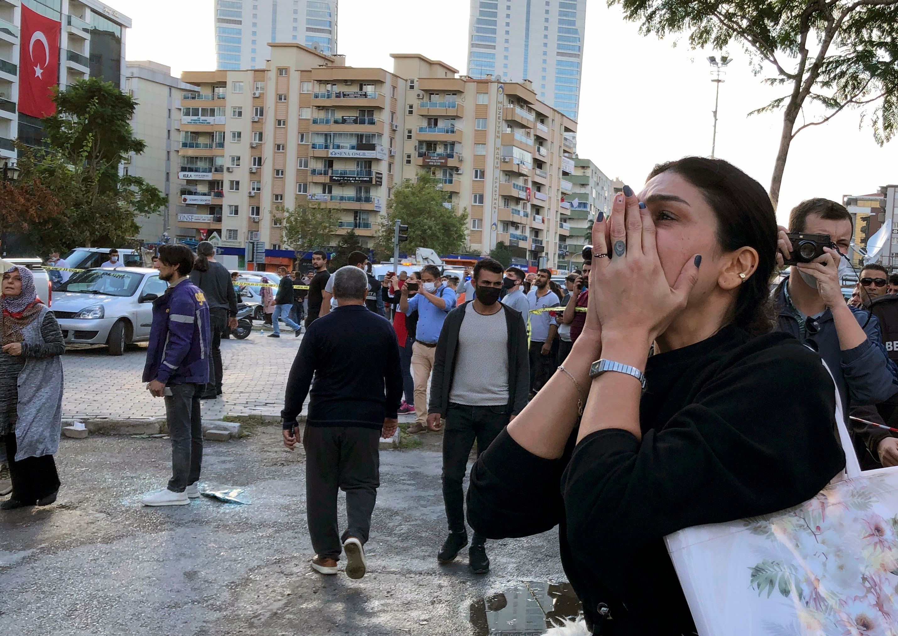 A woman watches as rescue workers try to save people trapped in the debris of a collapsed building, in Izmir, Turkey, Friday, Oct. 30, 2020