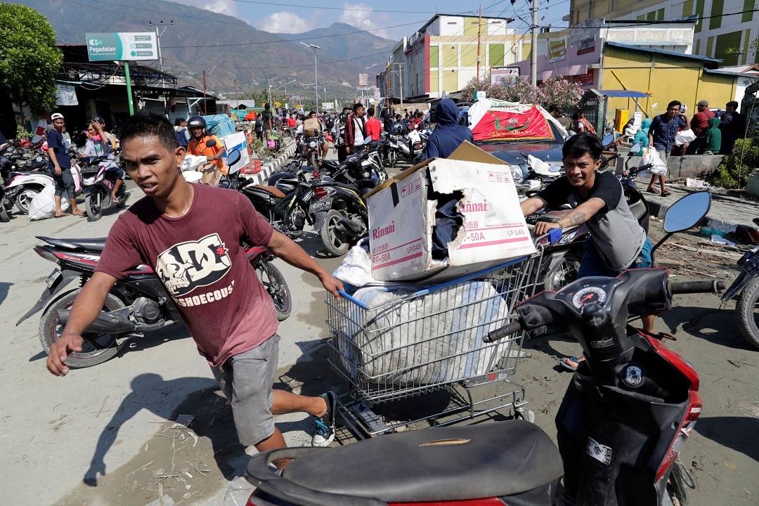 Indonesian men drag a shopping trolley with goods looted from a tsunami-devastated shopping mall in Palu. Indonesian men drag a shopping trolley with goods looted from a tsunami-devastated shopping mall in Palu.