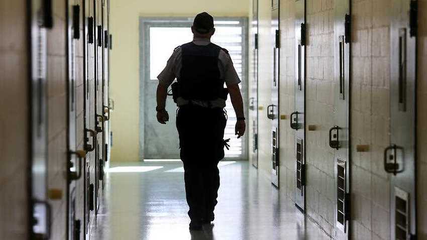 A corrections officer walks down a cell corridor. (Stock Image)
