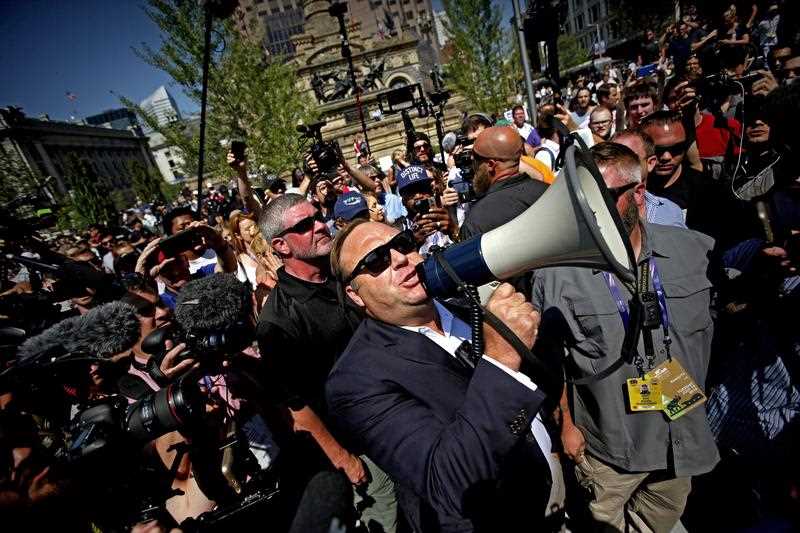 US radio host Alex Jones (C) uses a megaphone to speak to crowds near the Quicken Loans Arena, the venue for the 2016 Republican National Convention. US radio host Alex Jones (C) uses a megaphone to speak to crowds near the Quicken Loans Arena, the venue for the 2016 Republican National Convention.