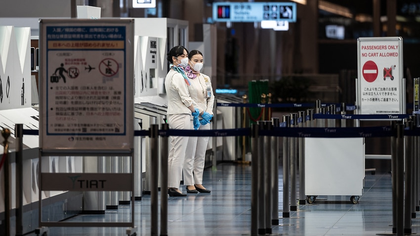 Staff members stand at the departure gate of Tokyo's Haneda international airport on 29 November, 2021.