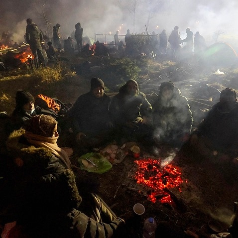 Migrants warm themselves near a fire at the Belarus-Poland border