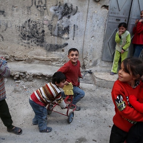 Syrian children play outside their home at the rebel-held neighborhood of Tishreen, after a ceasefire that went into effect in Damascus, Syria
