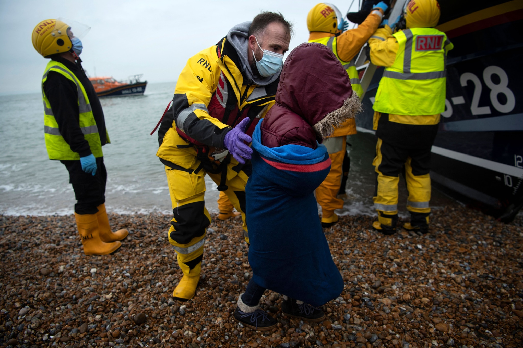 A child is helped ashore from a lifeboat at a beach in Dungeness, on the south-east coast of England, on 24 November, 2021.