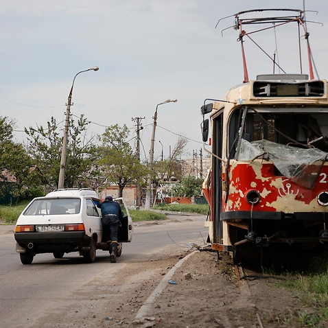 A man pushes a stalled car past a damaged tram in Mariupol (AP Photo/Alexei Alexandrov)