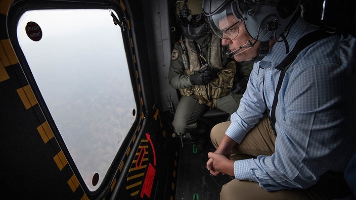 Prime Minister Scott Morrison tours the NSW fire zones in a military helicopter. The Morrison government has announced that rural New South Wales fire service volunteers will be compensated for loss of income, after weeks of pressure. 