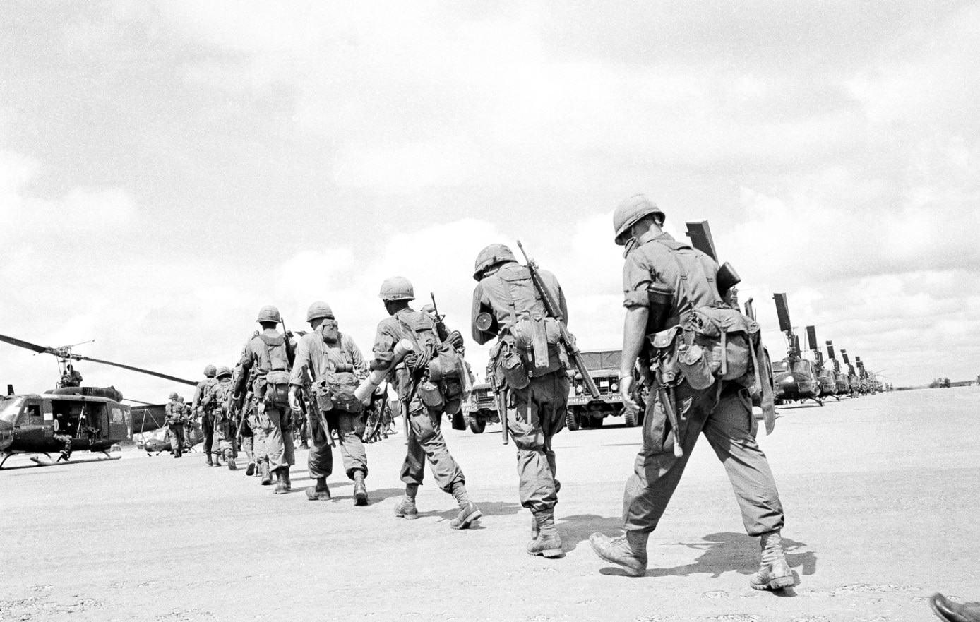 Paratroopers, heavily loaded with their packs, rations for several days and mortar ammunition walk in file across the Bien Hoa airfield, Vietnam in 1965. Paratroopers, heavily loaded with their packs, rations for several days and mortar ammunition walk in file across the Bien Hoa airfield, Vietnam in 1965.