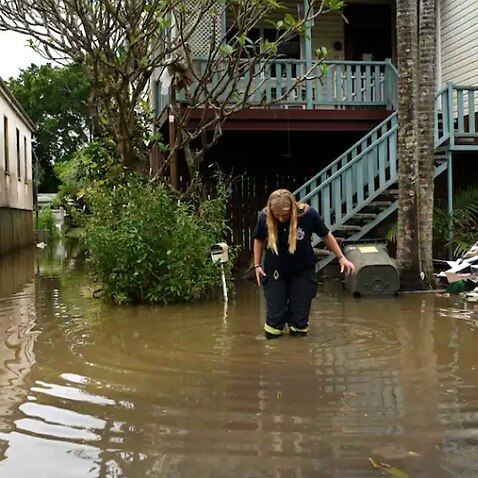 A rural fire service volunteer inspects a house surrounded by floodwater on 31 March, 2022 in Lismore, NSW.