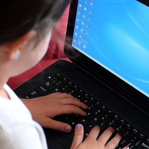 Image of a child looking at her laptop screen.