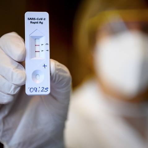 A health worker shows a positive result from a Rapid Antigen Test 