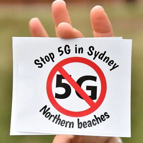 Anti 5G sticker being held by a member of Stop 5G Northern Beaches group.