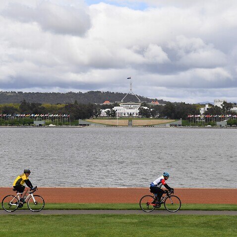Two cyclists ride through Commonwealth Park on the first day of easing of COVID restrictions in Canberra on 15 October 15. 
