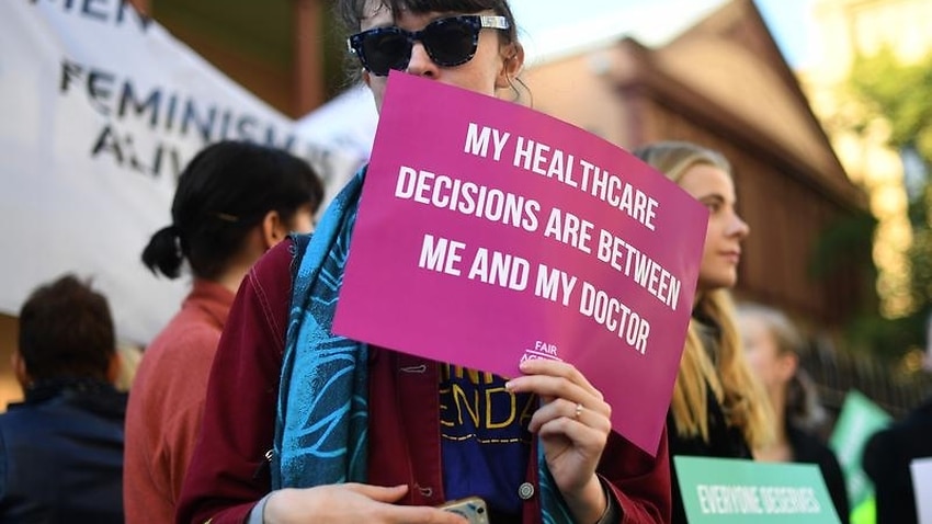 A demonstrator holds a placard in support of safe abortion zones.