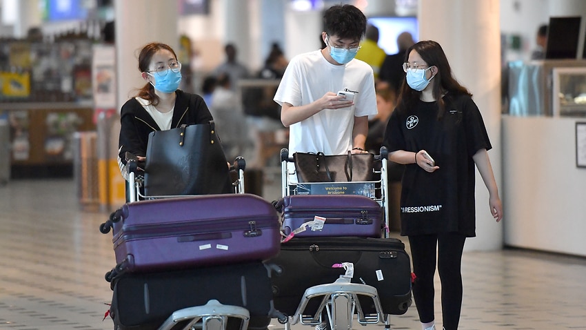 People wearing protective face masks are seen at Brisbane International Airport on Wednesday.