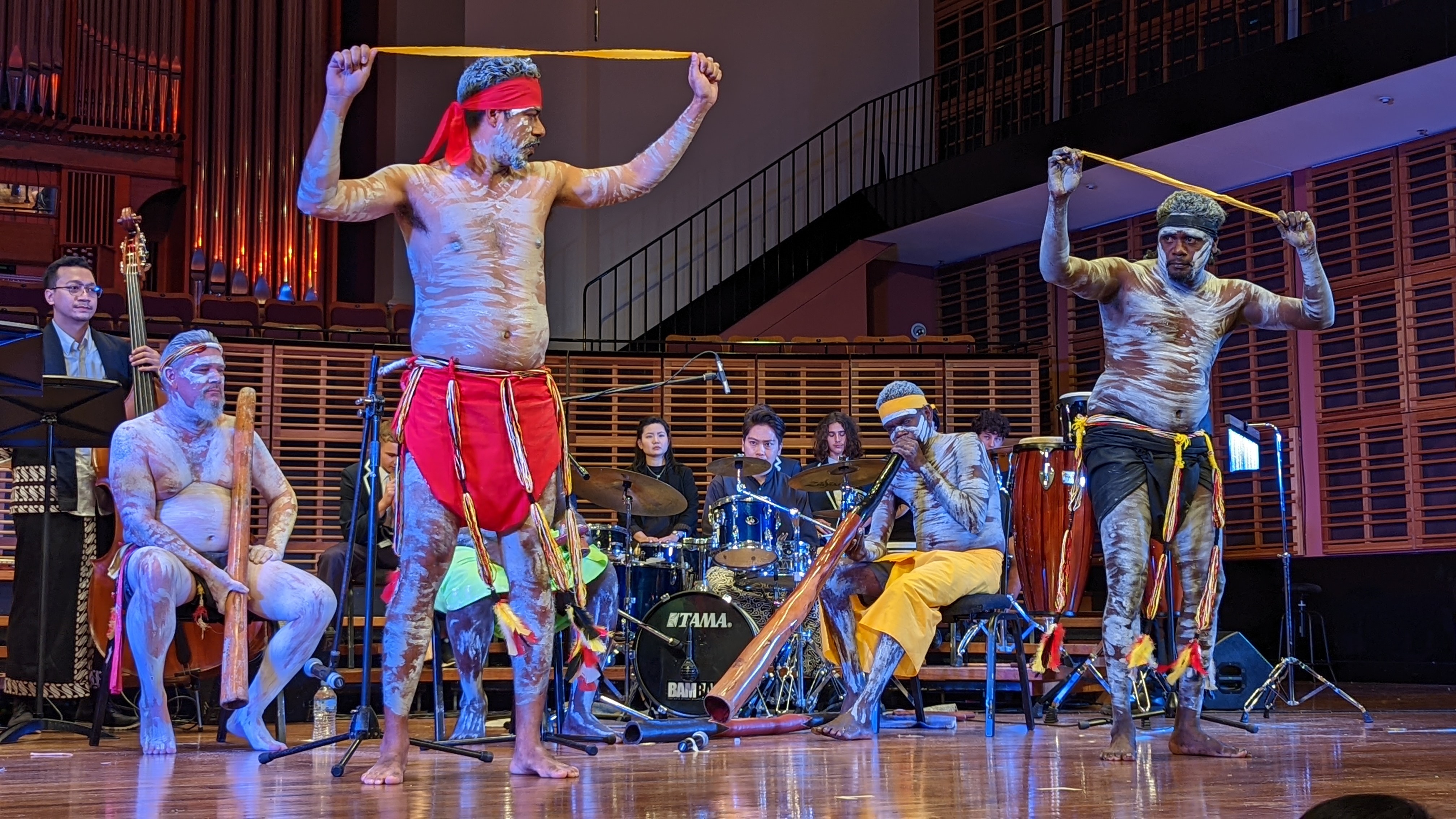 Yolngu man, Arian Pearson (standing, left) performs an aboriginal dance representing the colors brought by the Macassan people.