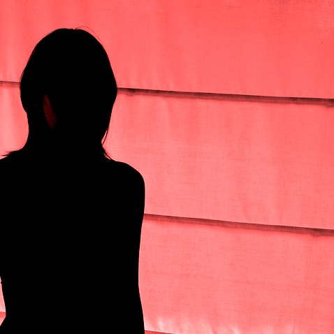 Silhouetted view of woman standing at red light district