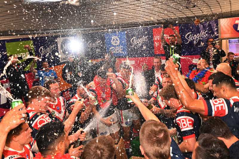 The Roosters celebrate in their dressing room after their win over the Storm during the 2018 NRL Grand Final between the Sydney Roosters and the Melbourne Storm at ANZ Stadium in Sydney, Sunday, September 30, 2018.