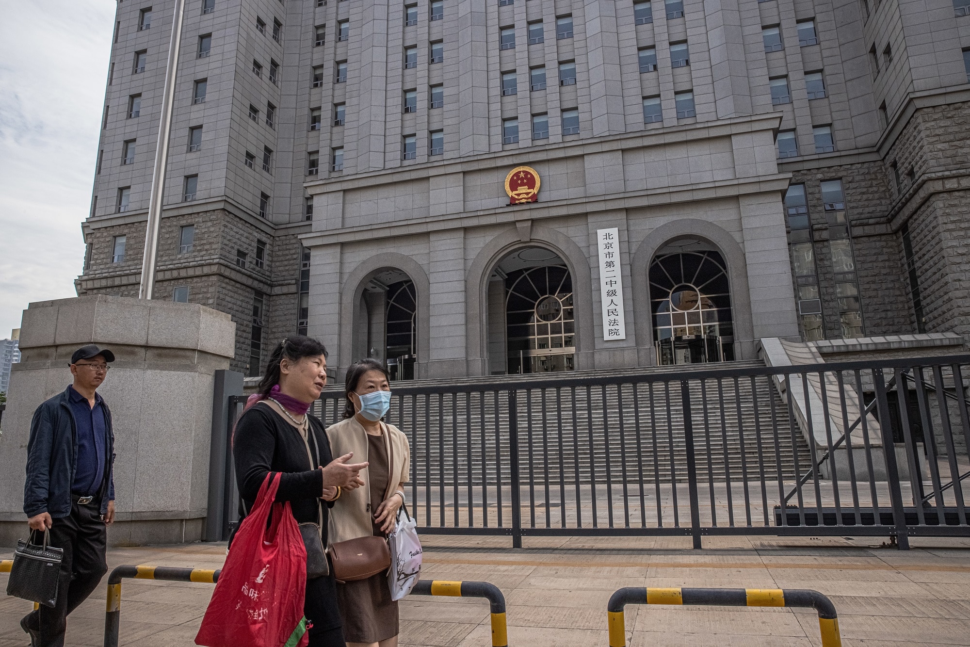 People walk past the Intermediate People's Court in Beijing where Yang Hengjun's trial is being held. 