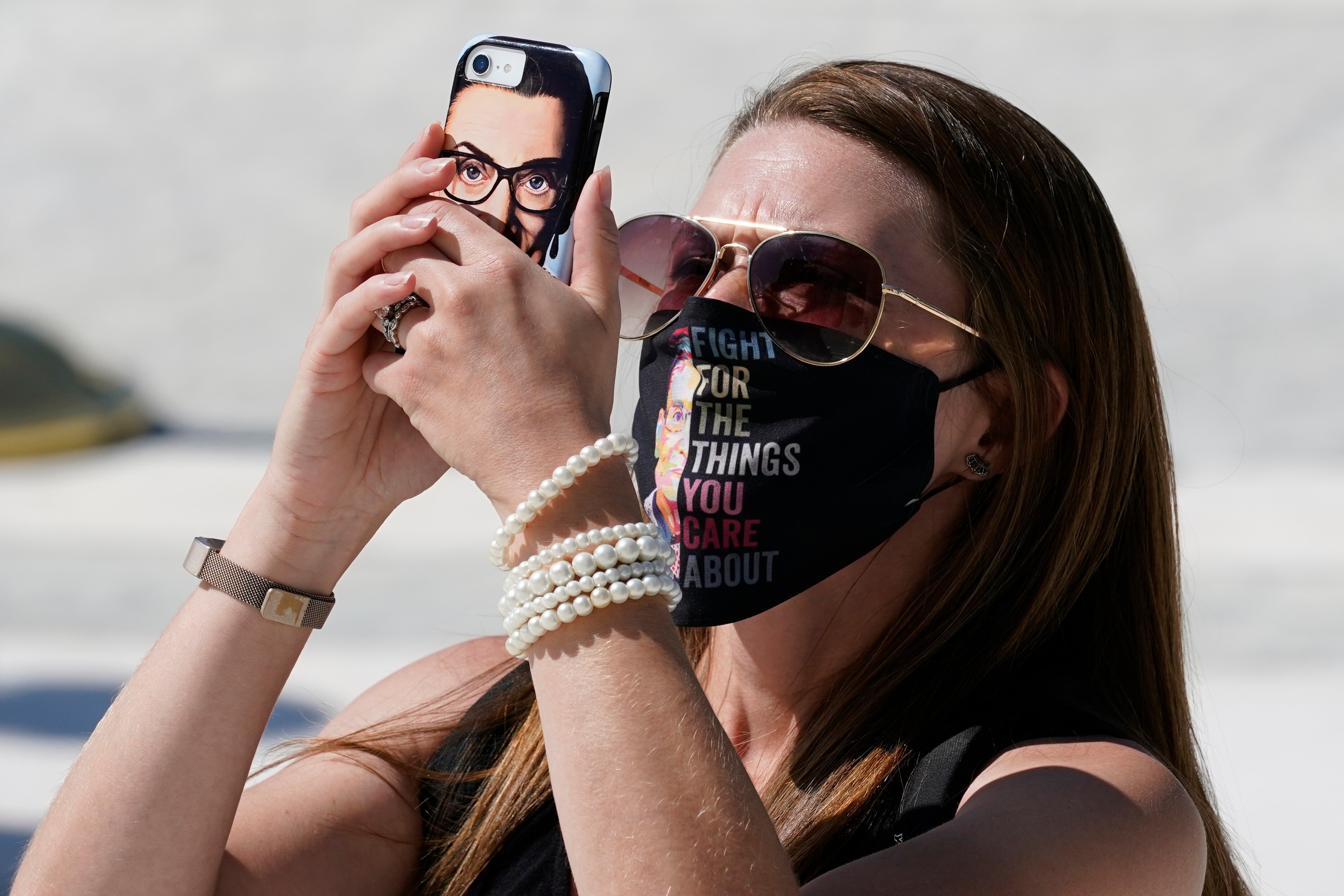 With an image of the late Justice Ruth Bader Ginsburg on a phone case a person pays respects as Ginsburg lies in repose at the U.S. Supreme Court.