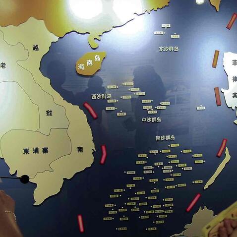Workers chat near a map of South China Sea on display at a maritime defense educational facility in Nanjing in east China’s Jiangsu province.