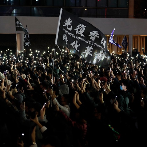 Protesters hold up their smartphone lights and their hands