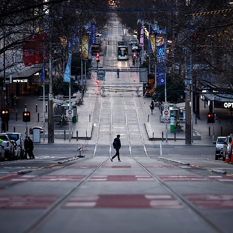 A person crosses a quiet Bourke Street in Melbourne amid a COVID-19 lockdown on Friday, 16 July, 2021. 