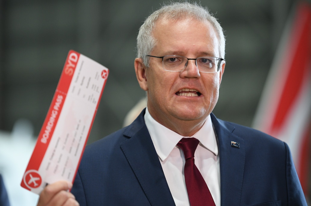 Prime Minister Scott Morrison holds up a novelty 'Ticket to Recovery' boarding pass during an announcement at Sydney Airport in March