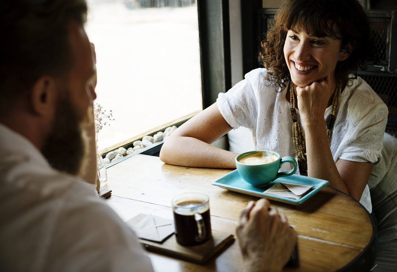 Woman smiling to a man while they're having coffee