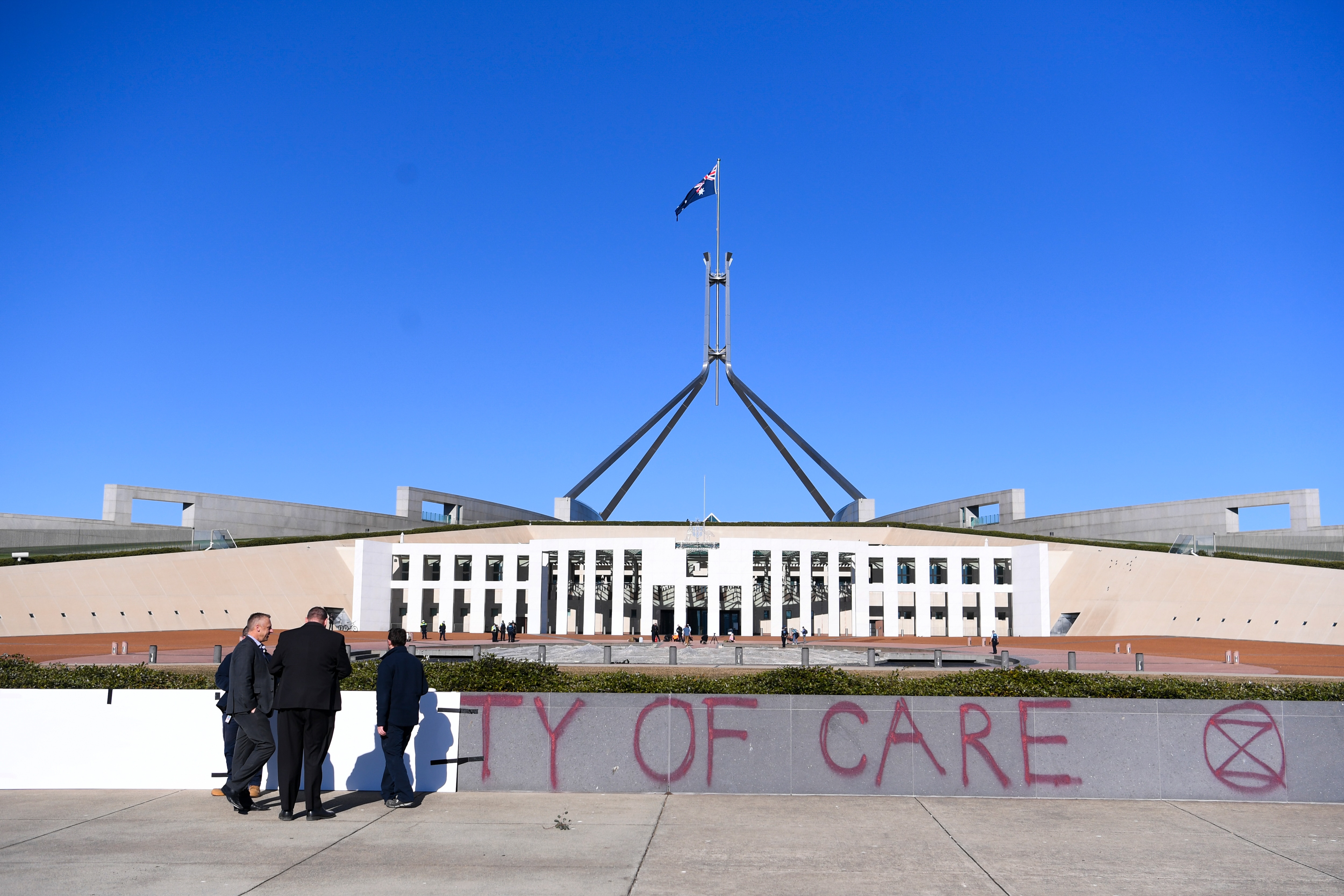 Workers cover the slogan Duty of Care after an Extinction Rebellion protest outside Parliament House.