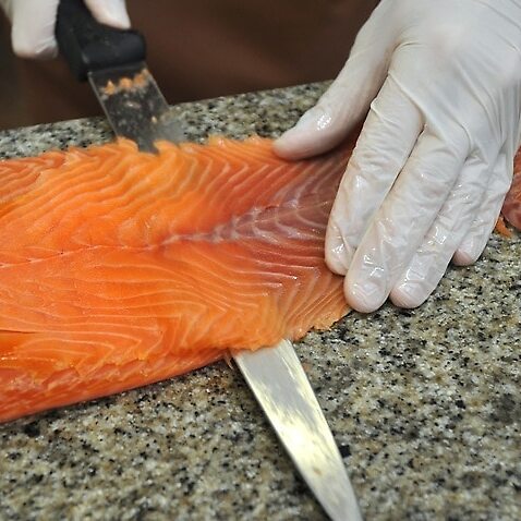 Image of smoked salmon being sliced be a knife.