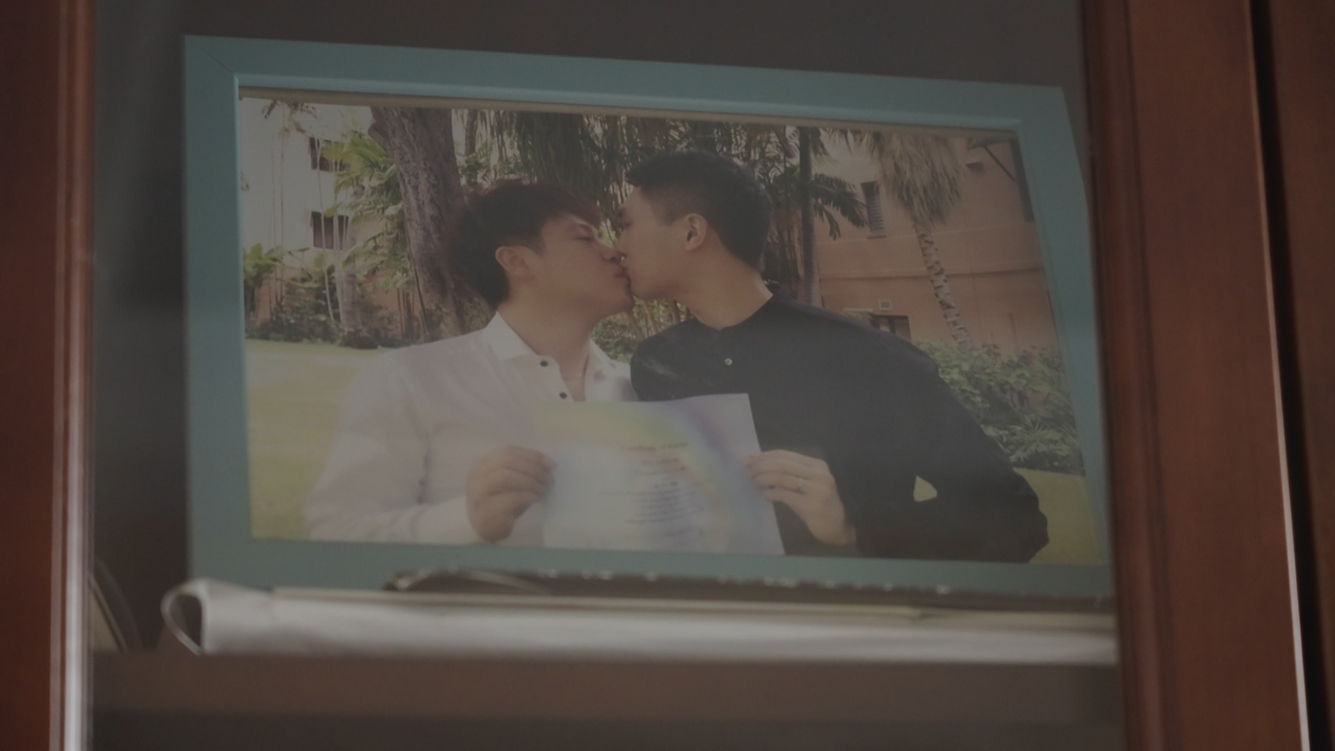 Hanson and Wu with their marriage certificate. Male couple in China kiss while holding marriage certificate