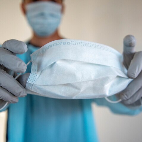 A health care worker holds a face mask.