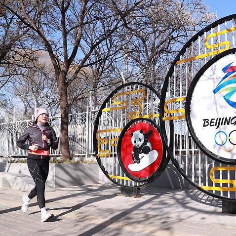 A jogger runs by a street decoration for the Beijing 2022 Winter Olympics at National Olympic Sports Center on 24 November, 2021 in Beijing, China. 