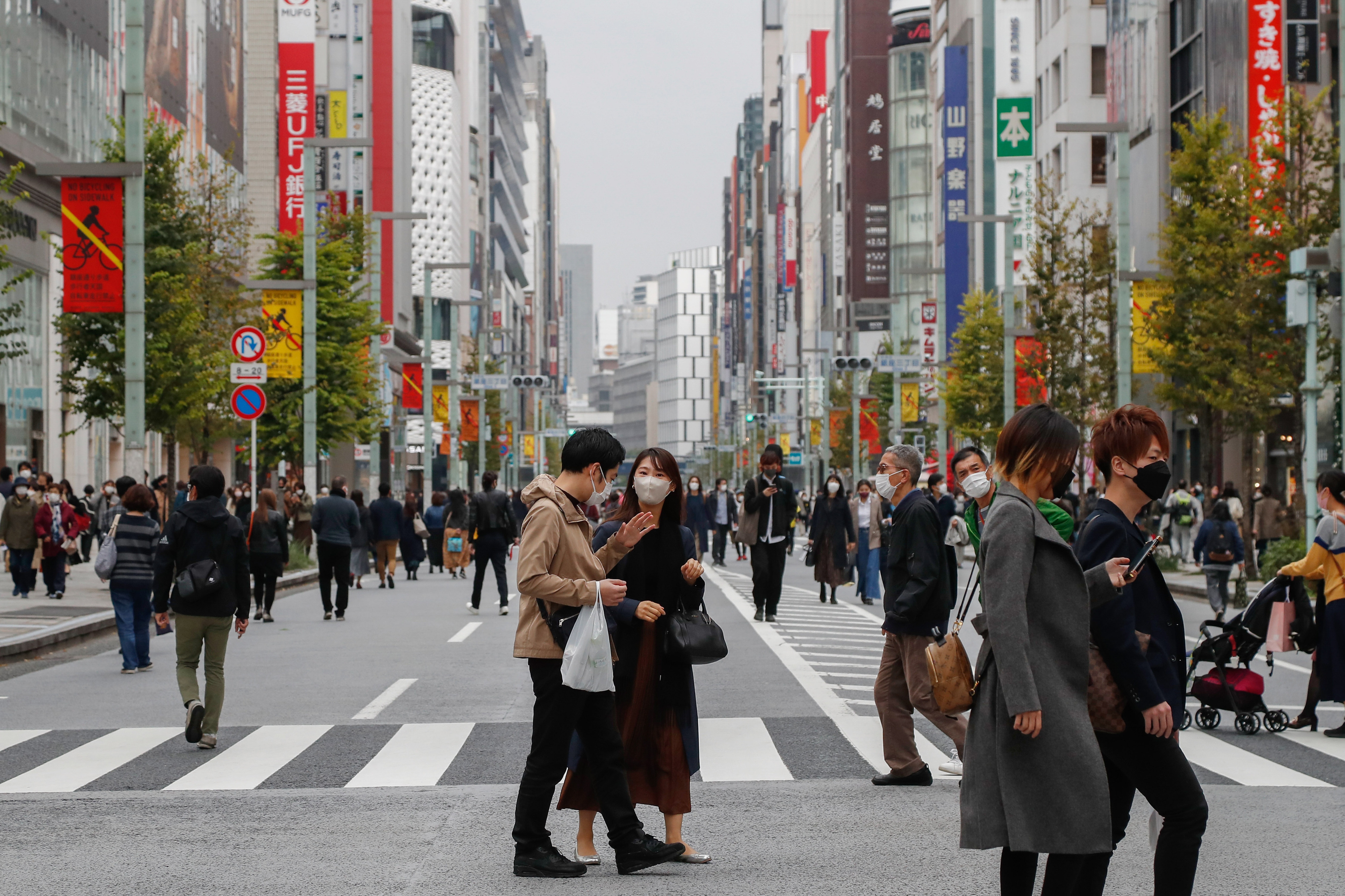 People wearing face masks as a preventive measure against the spread of coronavirus cross the street at Tokyo's Ginza fashion district.