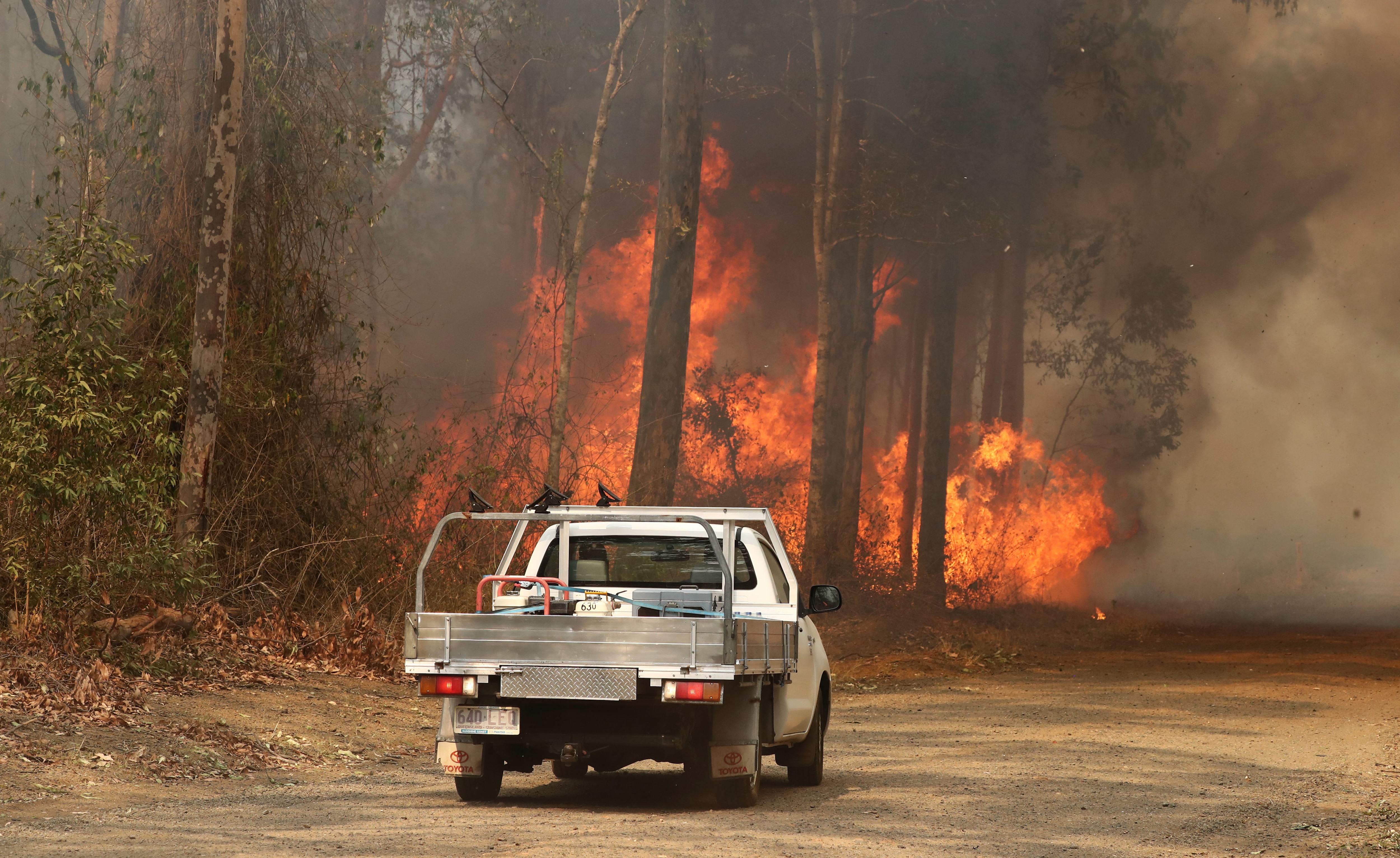 **RE-TRANSMISSION** Local residents are seen near a bushfire burning next to Busby's Flat Road in Busbys Flat, northern NSW, Wednesday, October 9, 2019. (AAP Image/Jason O'Brien) NO ARCHIVING