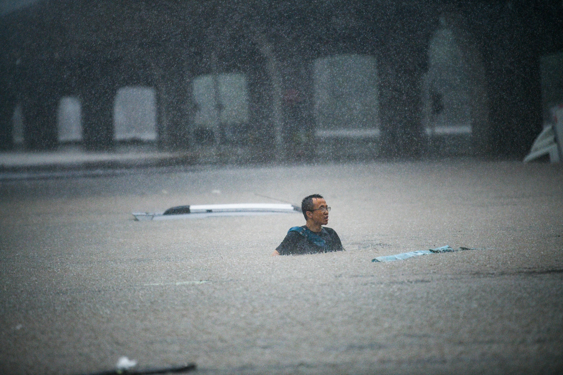 A person tries to swim across floodwaters caused by torrential rain in Zhengzhou, China, on 20 July 2021.