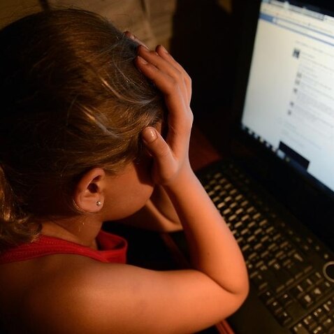 an upset young girl in front of a personal computer