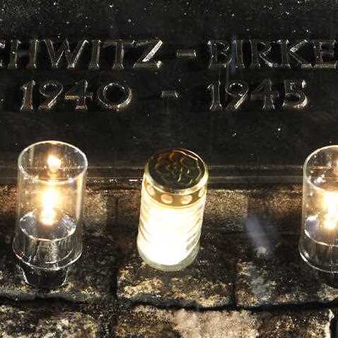 Candles burn by a memorial plaque at the Birkenau Nazi death camp in Poland.
