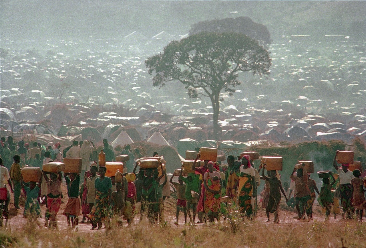 Refugees who fled the genoci in neighboring Rwanda carry water containers back to their huts at a refugee camp in Tanzania, near the border with Rwanda.