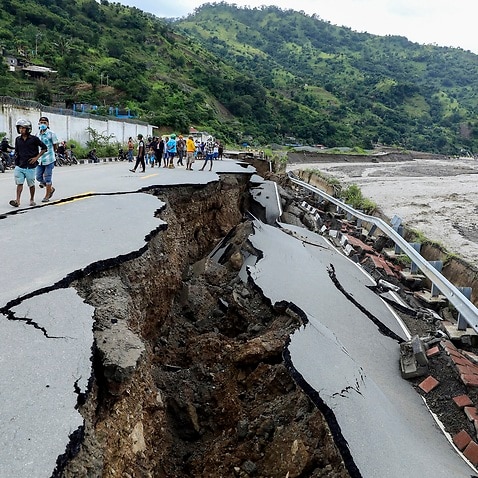 Officials inspect a damaged road in the aftermath of floods in Dili, Timor Leste