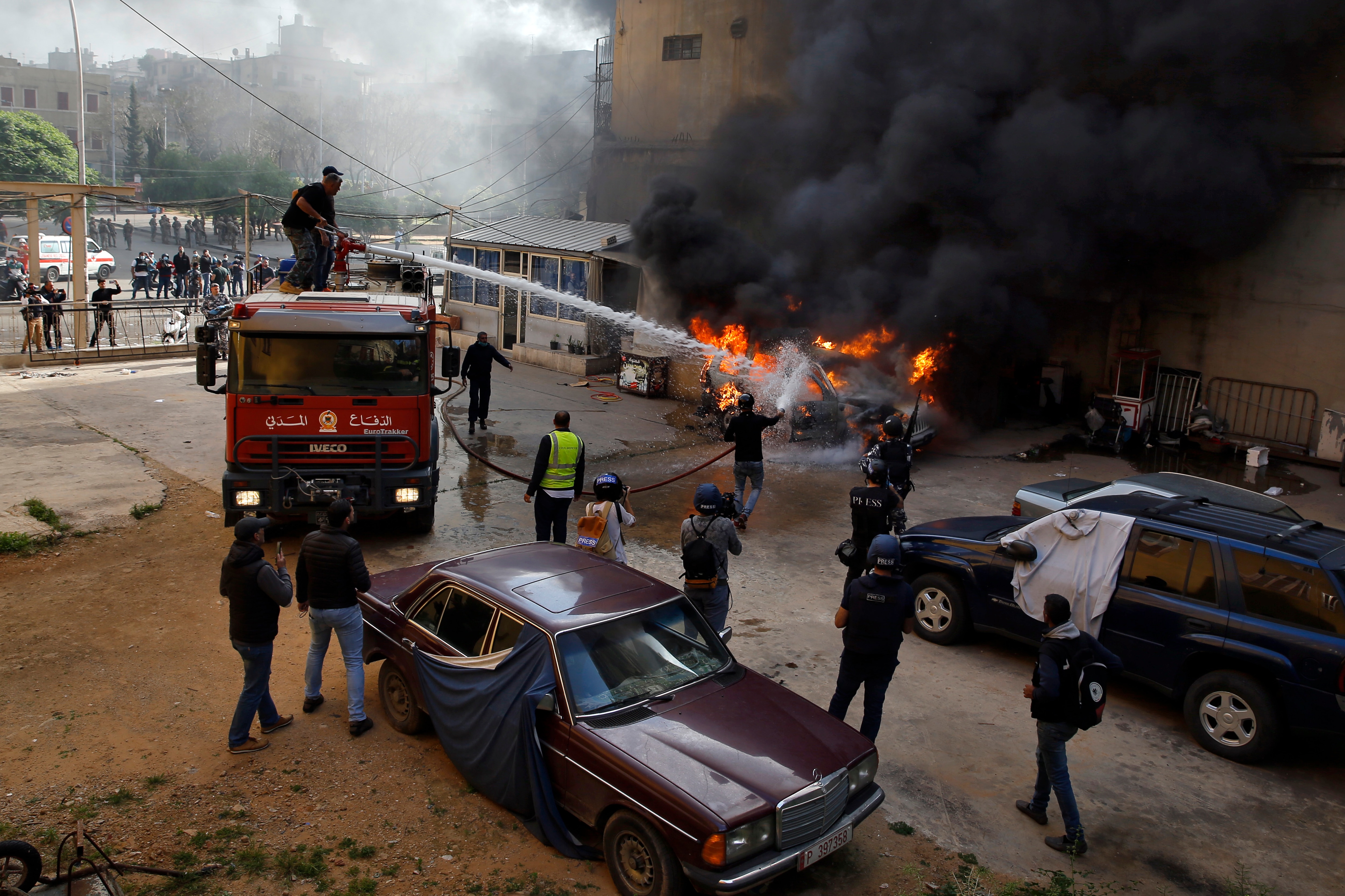 Firefighters extinguish a police car that was set on fire by anti-government protesters, in the northern city of Tripoli in Lebanon. 
