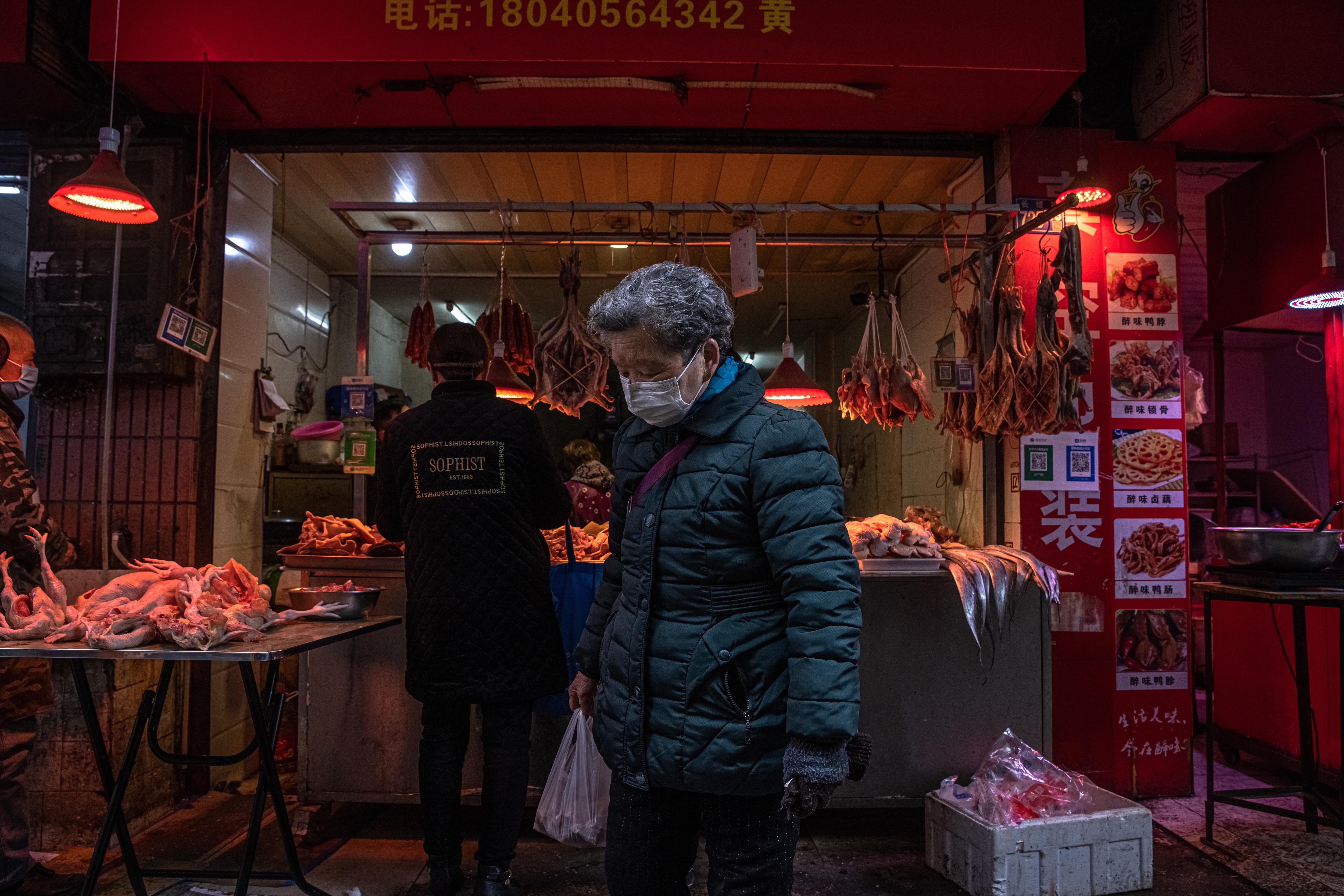 A woman wearing a protective face mask walks at a market in a residential area, in Wuhan, China, on 22 January 2021. 