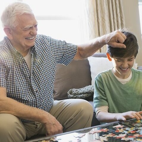 Playful grandfather and grandson solving puzzles
