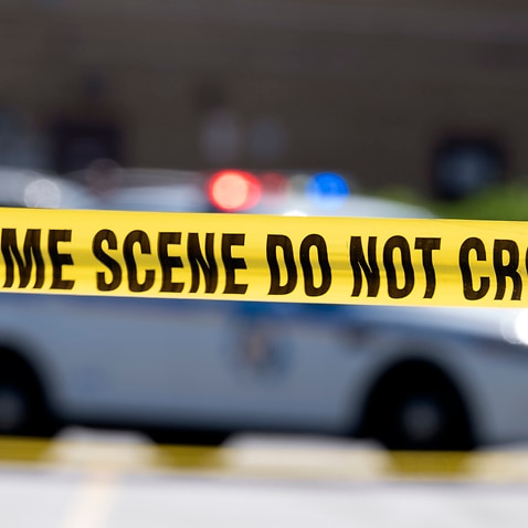 Yellow crime tape blocks off an area near a mall parking area where two Baltimore city police officers were shot and a suspect was killed as a U.S. Marshals task force served a warrant, Tuesday, July 13, 2021, in Baltimore, Md. The police officers were ta