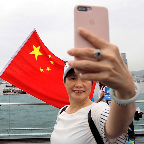 Pro-China supporters take a selfie with a Chinese national flag during a rally at a park in Hong Kong