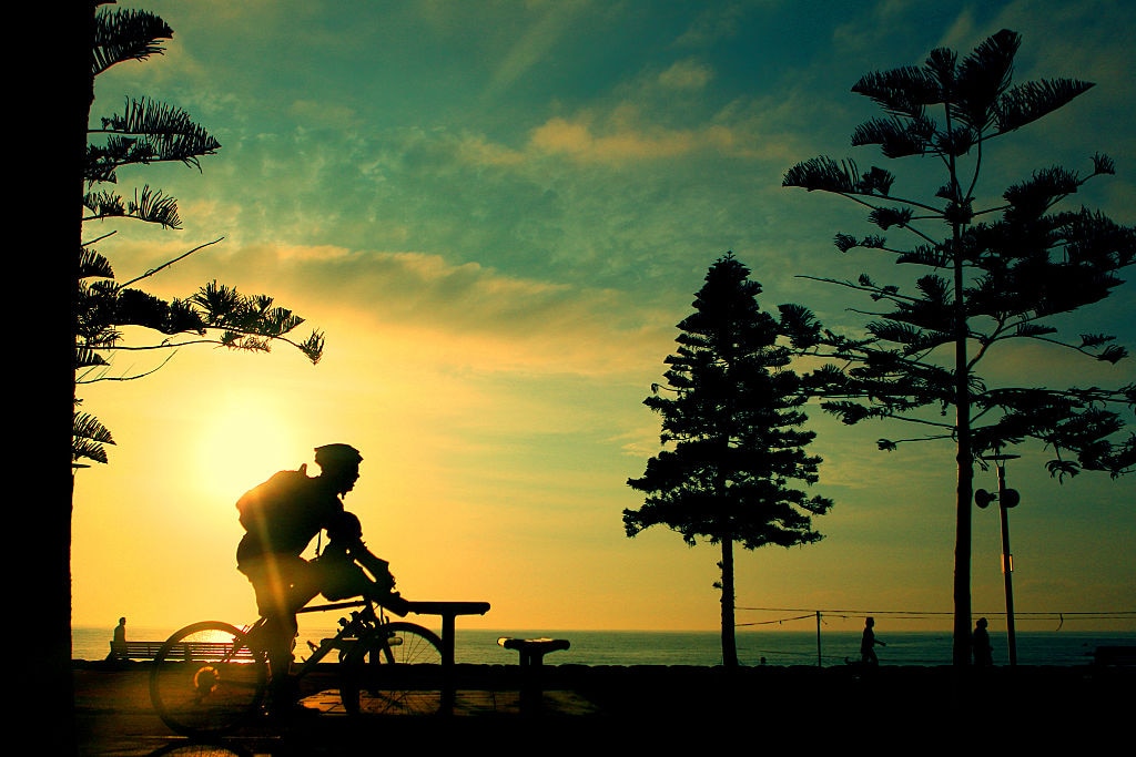 A man rides his bike at sunrise on Manly Beach, Sydney.