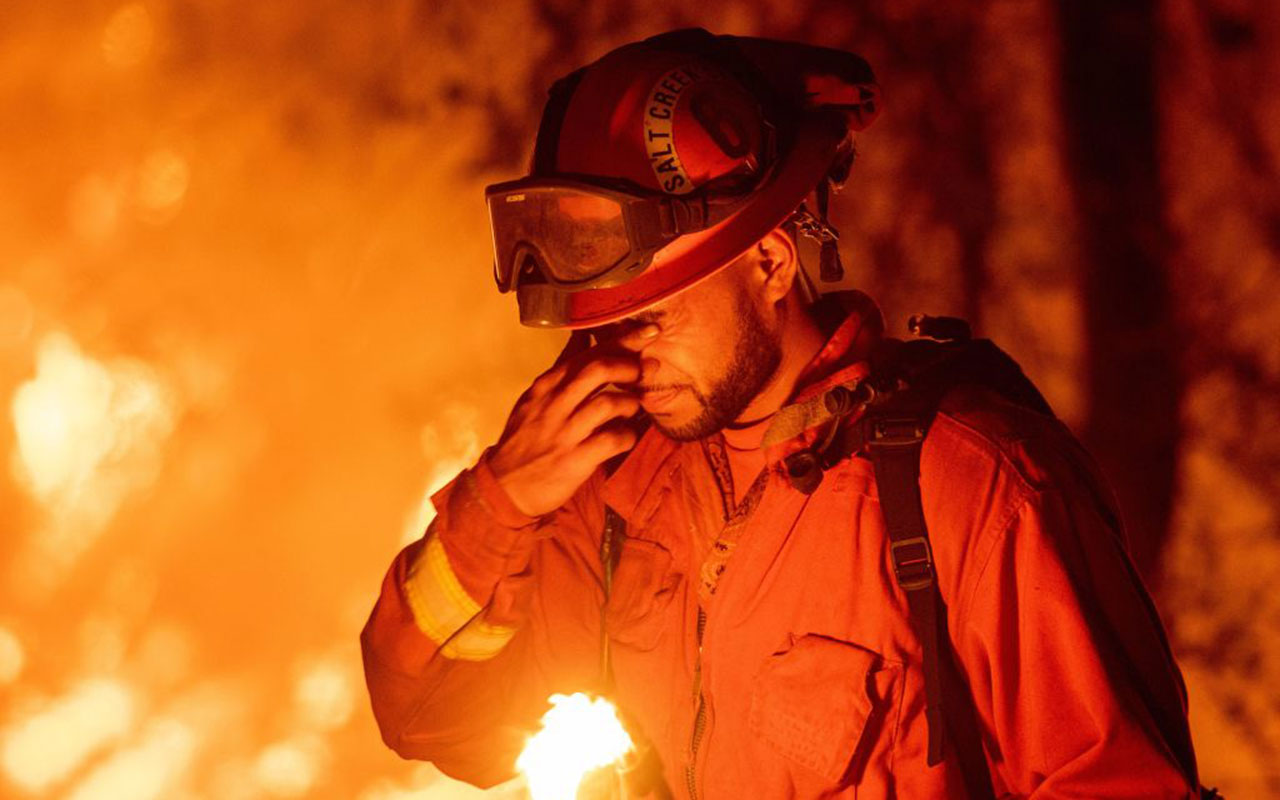  An inmate firefighter pauses during a firing operation as the Carr fire continues to burn in Redding, California on July 27, 2018.