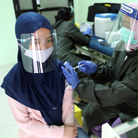 An elementary school student receives a tetanus vaccine shot from a health worker in Jakarta, Indonesia, Tuesday, Oct. 27, 2020.